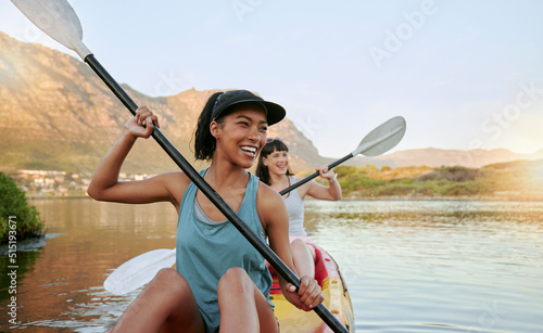 Slika na platnu Two smiling friends kayaking on a lake together during summer break
