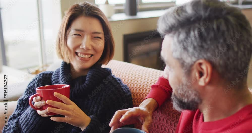 Happy diverse couple sitting in living room drinking coffee and talking Happy diverse couple sitting in living room drinking coffee and talking
