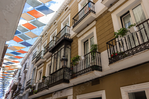 Badajoz, Spain, September 10, 2021: The San Juan street in Badajoz, Spain, with buildings with beautiful colorful banners hanging above the street. photo