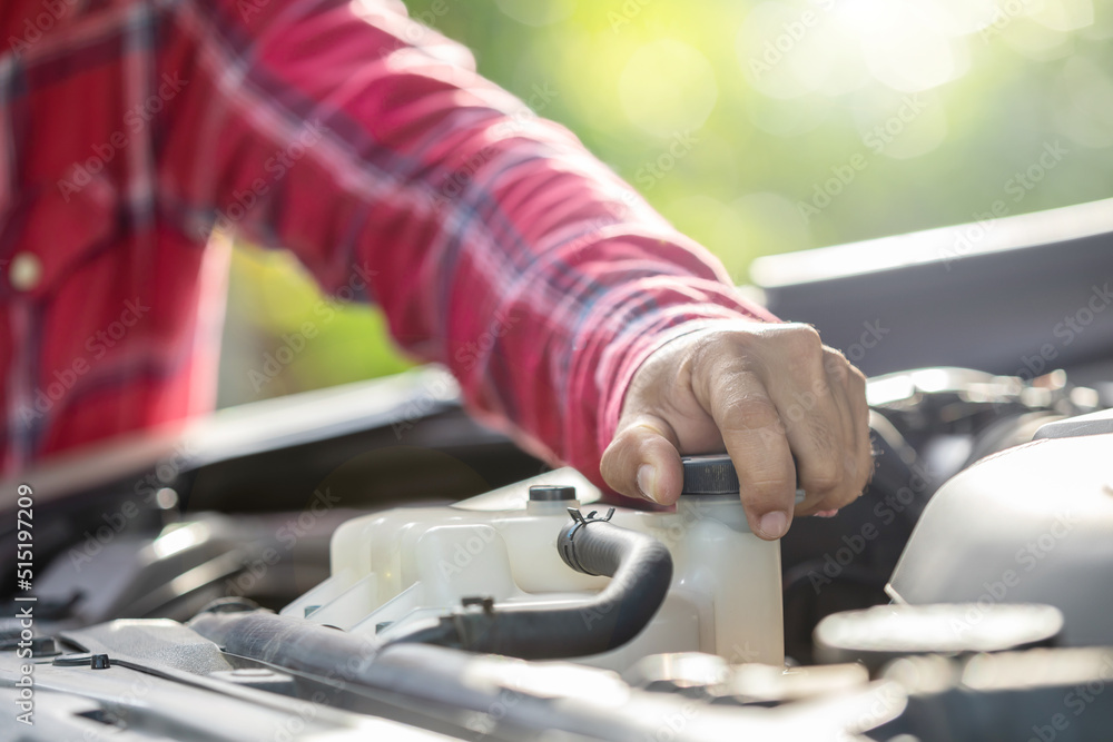 Man opening cap of car radiator to checking up the engine before start the trip. Car maintenance or check up concept Man opening cap of car radiator to checking up the engine before start the trip. Car maintenance or check up concept
