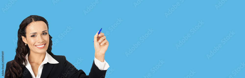 Portrait of happy smiling beautiful young businesswoman in black confident suit, writing or drawing something on screen, by marker. Brunette woman, isolated on blue background Portrait of happy smiling beautiful young businesswoman in black confident suit, writing or drawing something on screen, by marker. Brunette woman, isolated on blue background