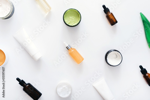 Top view layout of face and body skin care products. A variety of creams, lotions and serums on a white background. Home spa concept.