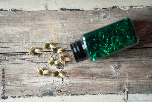 omega 3 capsules laying on wooden table with green bottle. Health and lifestye concept. photo