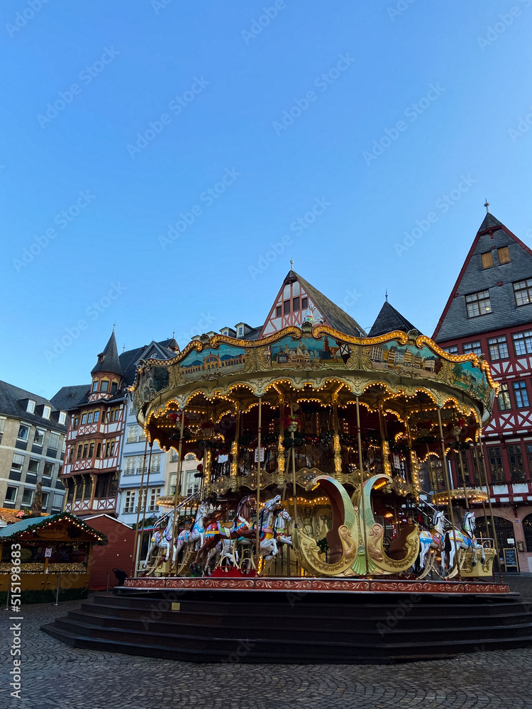 Frankfurt am Main, Germany, December 7, 2021: Traditional Christmas market and carousel at the Romerberg Square in Frankfurt. Merry-go-round in Christmas street fair on Romer historic square. Frankfurt am Main, Germany, December 7, 2021: Traditional Christmas market and carousel at the Romerberg Square in Frankfurt. Merry-go-round in Christmas street fair on Romer historic square.