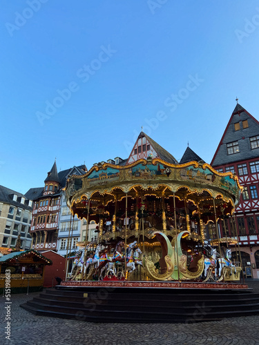Frankfurt am Main, Germany, December 7, 2021: Traditional Christmas market and carousel at the Romerberg Square in Frankfurt. Merry-go-round in Christmas street fair on Romer historic square.