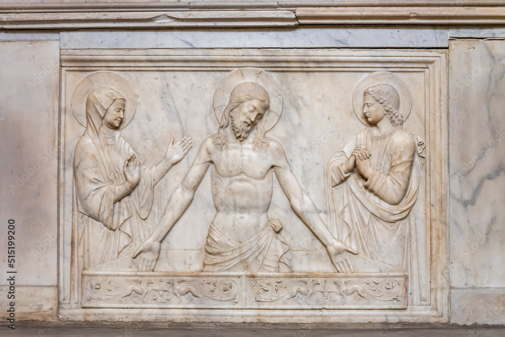 Religious scene carved in a marble wall inside a church in Napoli, showing Jesus Christ, Virgin Mary and a catholic saint reunited.