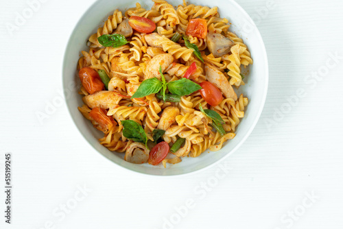 Close up Tasty Gourmet Spicy Pasta with Tomato and Herbs on a White Plate, Served on Top of a white wooden Table.