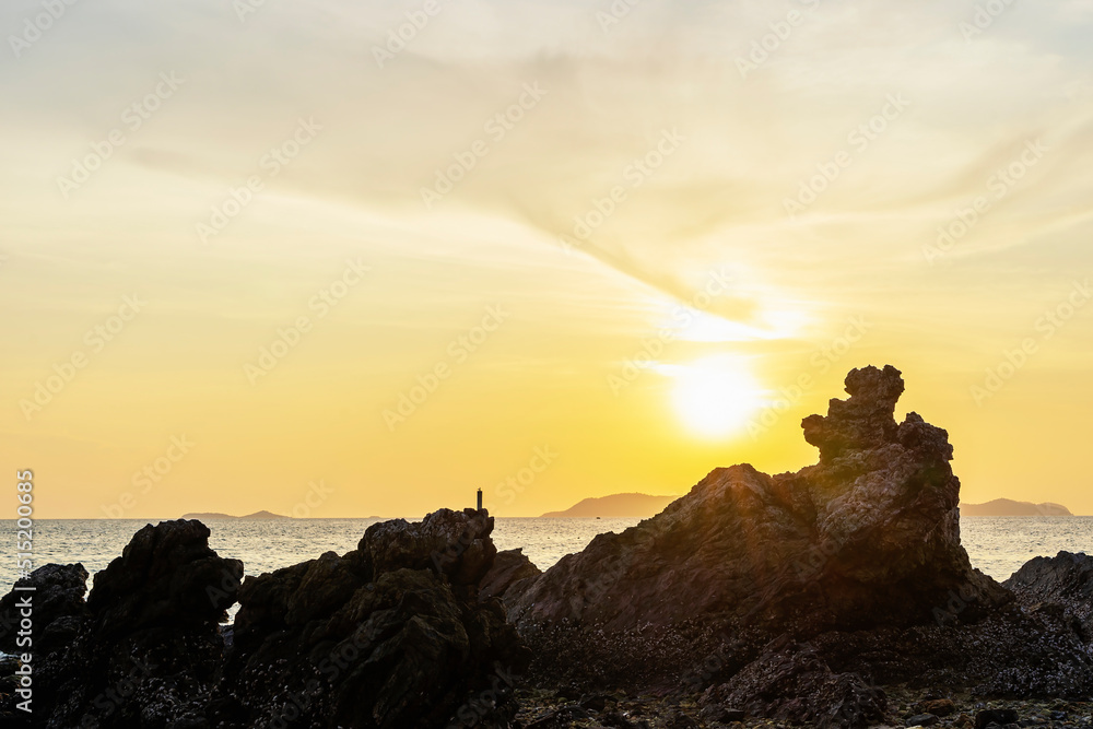 Close up of the foreground rock in front of the sea in twilight time. Silhouette rock on the beach against the sky during sunset. Sun setting on the horizon for freedom and beginning life concept.