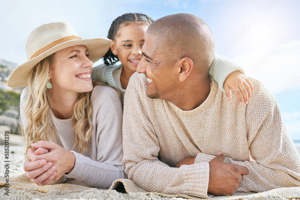 Fototapeta premium Smiling married couple bonding with daughter on the beach. Cute adorable little girl embracing and lying on her mother and father outside. Happy husband and wife enjoying free time with their child