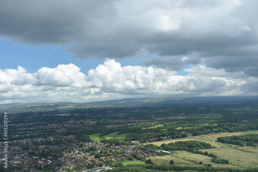 Aerial view from a helicopter with green fields and buildings in the distance. Manchester England. 
