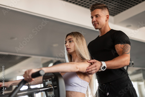 Beautiful blonde fitness woman with a handsome sporty instructor man work out and train together in the gym
