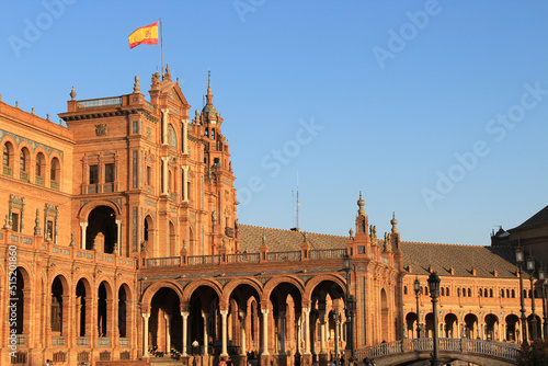 Seville, Spain, September 11, 2021: The Spanish Steps in Seville or 'Plaza de España', where the main building of the Ibero-American Exhibition of 1929 was built. Spanish flag at sunset.