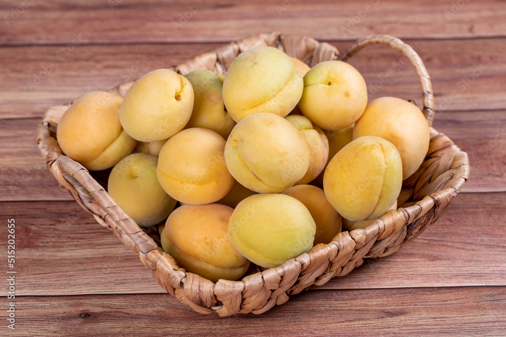 Apricots on wood background. A pile of fresh apricots in a basket. close up Apricots on wood background. A pile of fresh apricots in a basket. close up