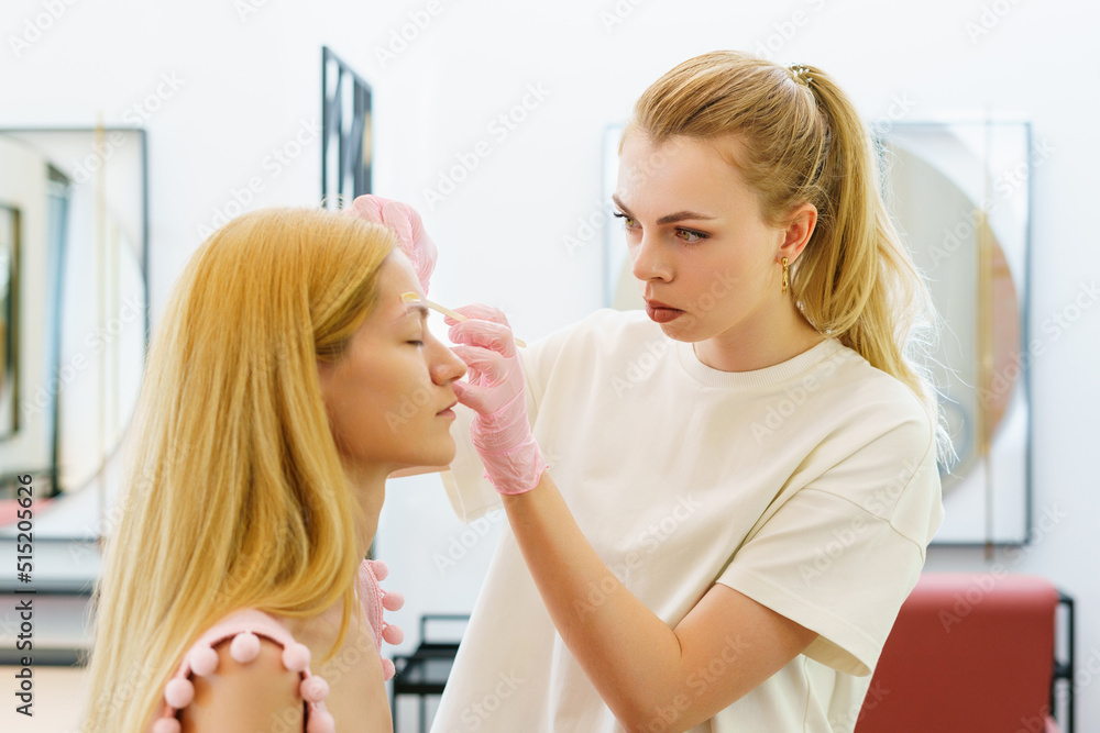 The eyebrow master removes facial hairs using wax. Beauty procedures The eyebrow master removes facial hairs using wax. Beauty procedures