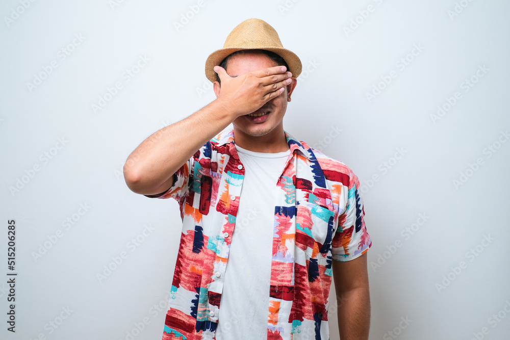 Asian man covering one eye with hand, confident smile on face and surprise emotion. Asian man covering one eye with hand, confident smile on face and surprise emotion.
