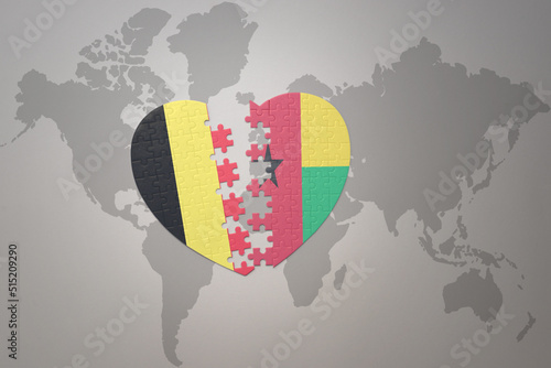 puzzle heart with the national flag of belgium and guinea bissau on a world map background.Concept.