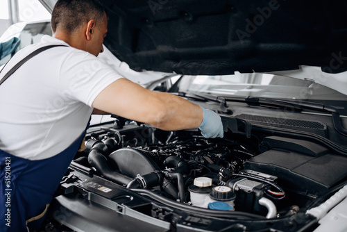 Car service mechanic worker standing in front of car engine open hood and working