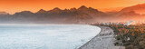 Sunset panoramic view of scenic and popular Konyaalti beach in Antalya resort town. Majestic mountains with haze in the background. Vacation and holiday in Turkey