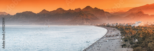 Sunset panoramic view of scenic and popular Konyaalti beach in Antalya resort town. Majestic mountains with haze in the background. Vacation and holiday in Turkey
