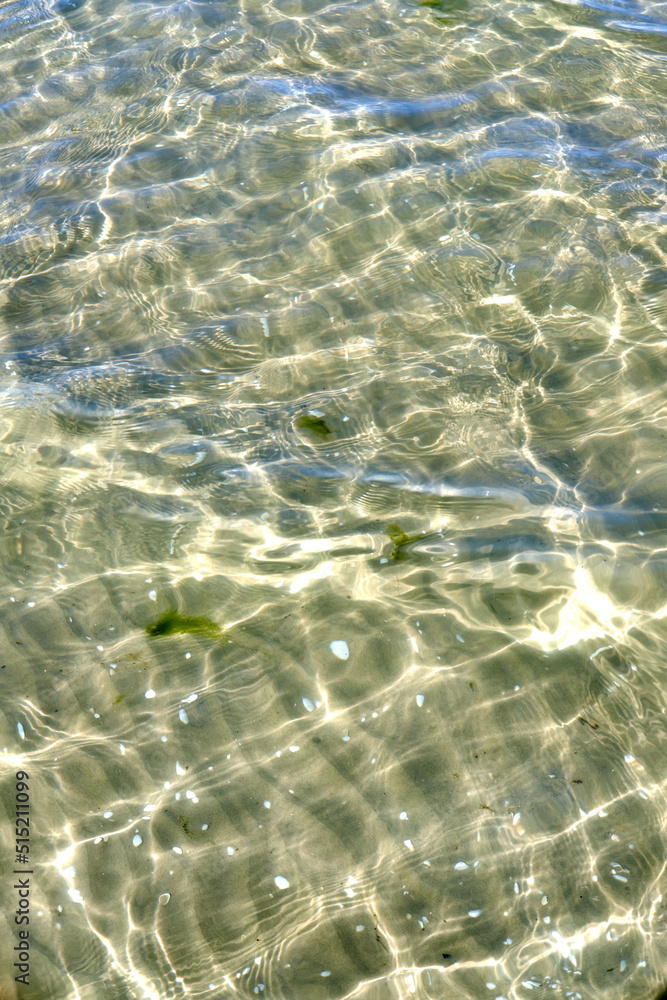 Above view of sunlight reflecting on water at beach. Closeup of shallow waves and calm ripples on coastline on sunny day outside. Clear liquid refracting sun rays in summer for copy space background