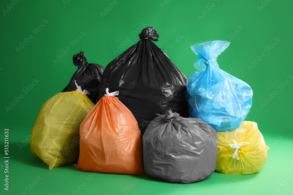 Trash bags full of garbage on green background