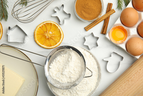Flat lay composition with cookie cutters and ingredients on white table. Christmas biscuits
