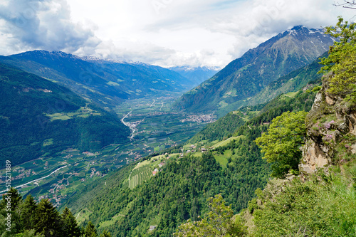 a hiking trail overlooking the alpine valley of the city Merano surrounded by the Texel group mountains (Oetztaler Alpen in Südtirol, South Tyrol, Italy)
