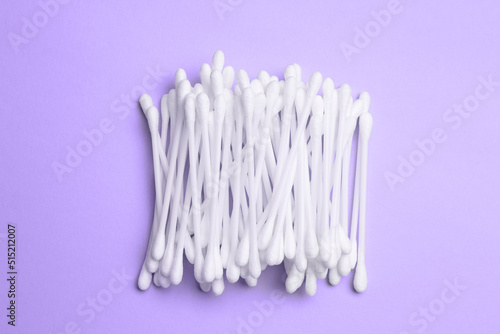 Heap of cotton buds on violet background, top view