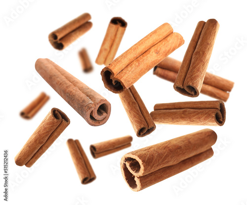 Aromatic cinnamon sticks falling on white background