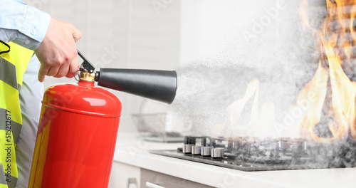 Man putting out burning cooktop with fire extinguisher in kitchen, closeup. Banner design