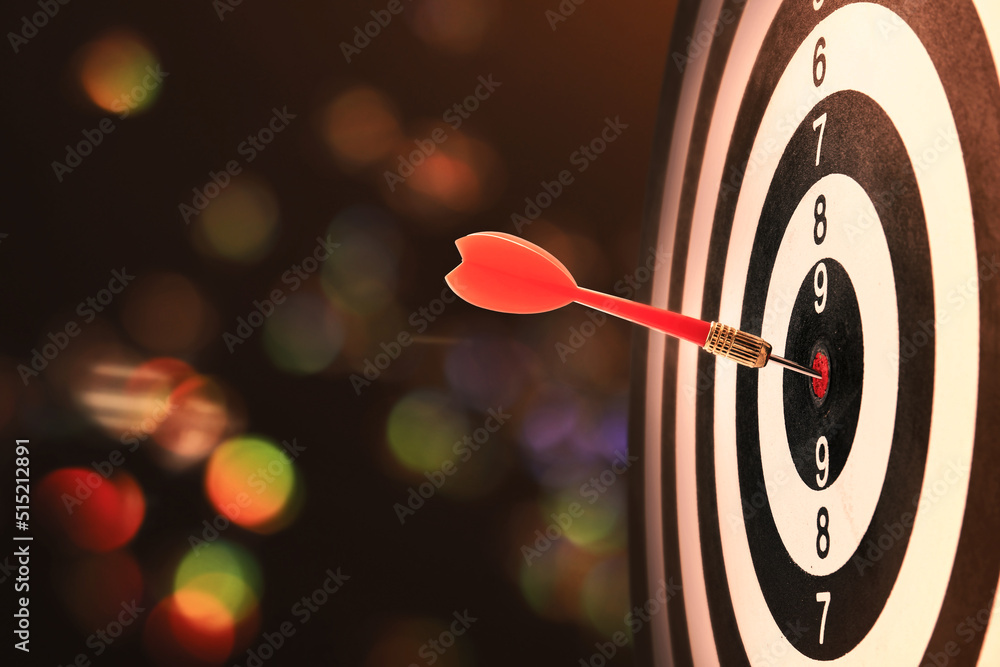 Red dart hitting target on board against blurred background Red dart hitting target on board against blurred background