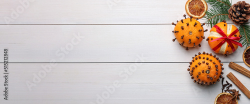 Pomander balls made of tangerines with cloves  spices and fir branches on white wooden table  flat lay with space for text. Banner design