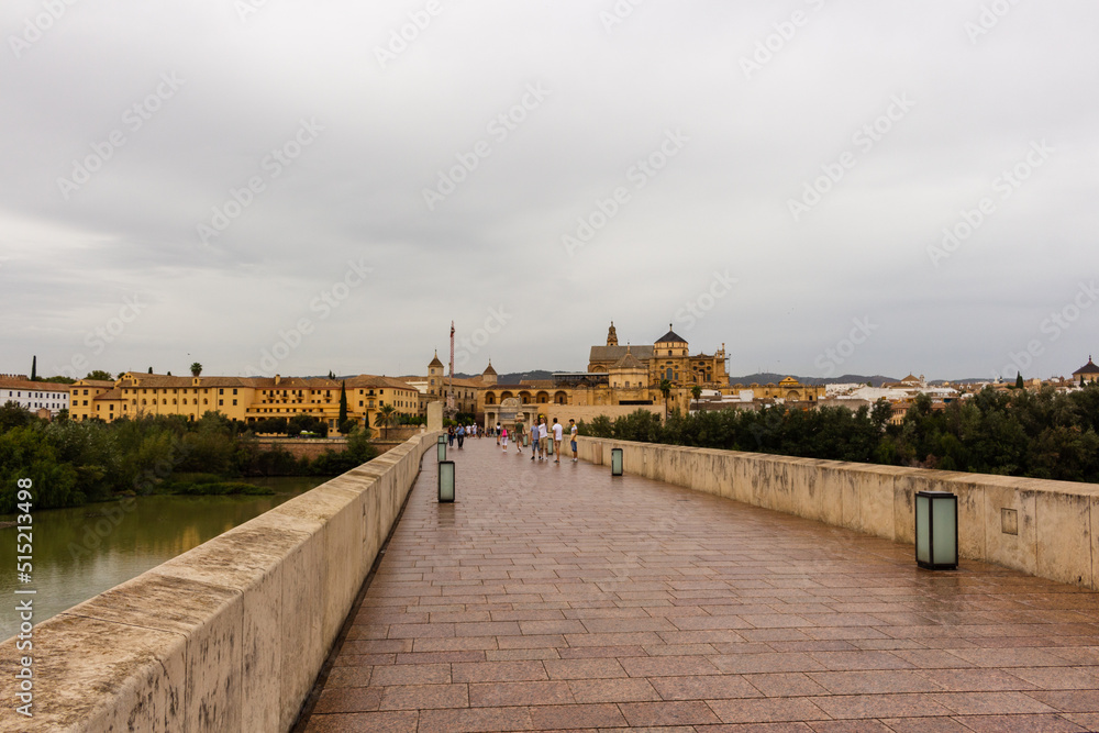 Fototapeta premium Cordoba, Spain, September 13, 2021: Guadalquivir River and the Roman Bridge, with Cordoba Mosque-Cathedral in the background.
