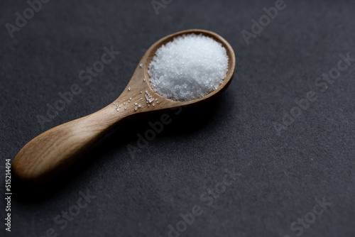 salt in a wooden spoon on black background. Selective focus	