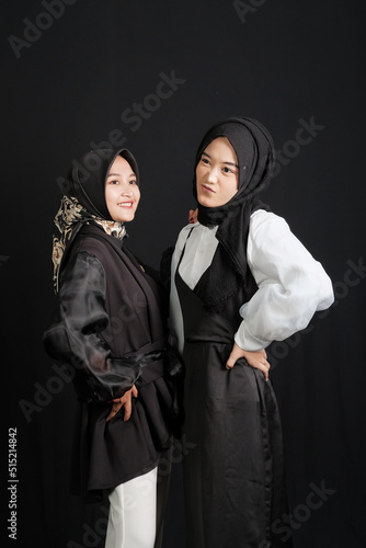 Two happy young Asian Muslim women isolated on black background.