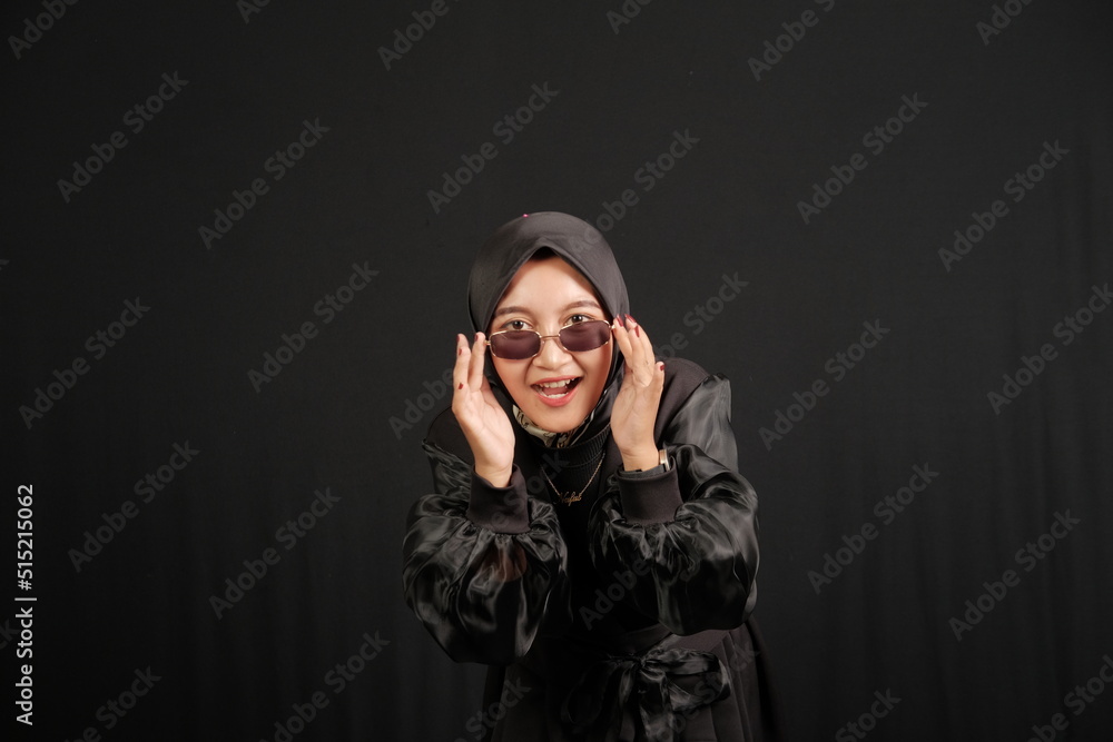 Happy young Asian Muslim woman wearing glasses isolated on black background. Happy young Asian Muslim woman wearing glasses isolated on black background.