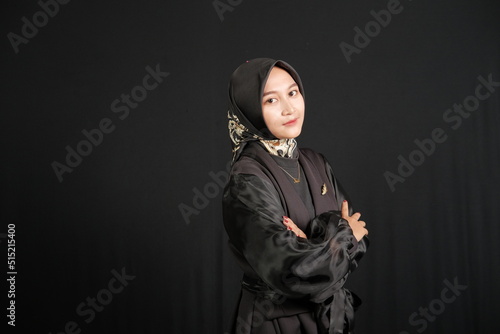 Portrait of Indonesian woman wearing hijab folding her hands, isolated on black background