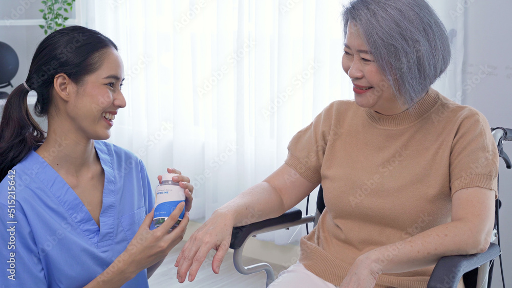 Portrait of young Asian nurse home care put medicine bottle to senior grandmother and start to explain about this medicine. Female caregiver take care of the elderly woman who sitting on wheelchair. Portrait of young Asian nurse home care put medicine bottle to senior grandmother and start to explain about this medicine. Female caregiver take care of the elderly woman who sitting on wheelchair.