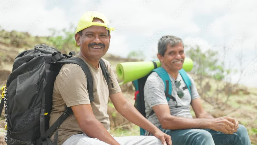 Happy smiling hikers or travellers with backpack looking at camera while trekking on mountain - concept of friendship, relaxation and leisure activities Happy smiling hikers or travellers with backpack looking at camera while trekking on mountain - concept of friendship, relaxation and leisure activities