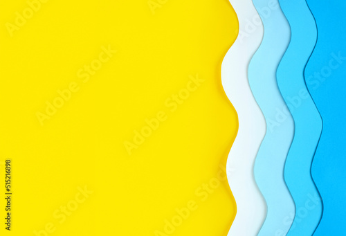 Yellow beach sand background with place for text and paper cut blue waves on right. Seashore made of color paper. Summer sea holidays concept. Relaxation and fun on vacation. The ocean coast layout.