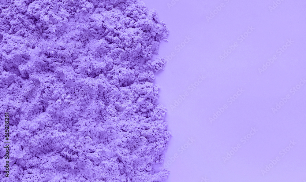 Violet kinetic sand on very peri color paper background with copy space. Early sensory education for children. Kids development concept. Inspired by trendy Pantone color of the year 2022 Very Peri.