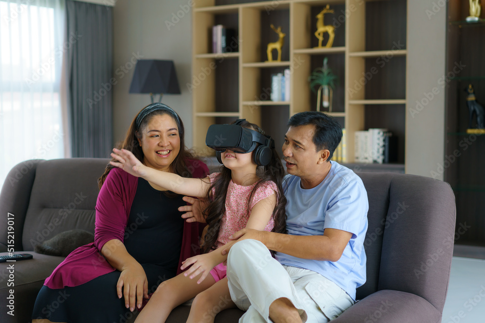 Asian family enjoy technology device hand use vr goggle glasses play fun together on sofa living room at home. Smart technology with lifestyle. Asian family enjoy technology device hand use vr goggle glasses play fun together on sofa living room at home. Smart technology with lifestyle.