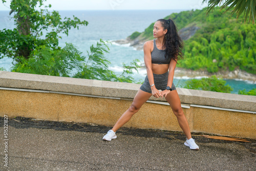 A Beautiful fit woman in sportswear exercising on seaside mountain peak, Health and Travel concept.