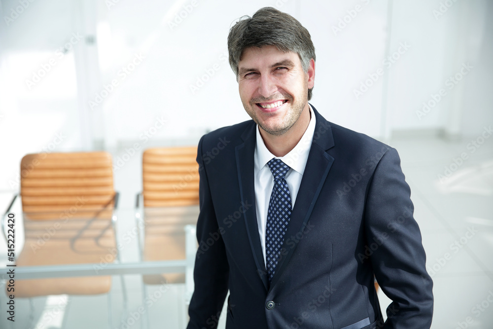 successful businessman standing by the desk. successful businessman standing by the desk.