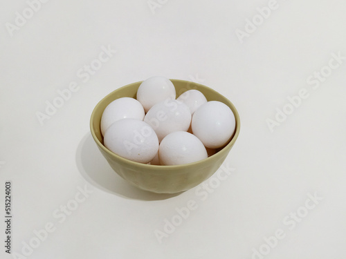 Many eggs, a bowl full of white eggs on a white background