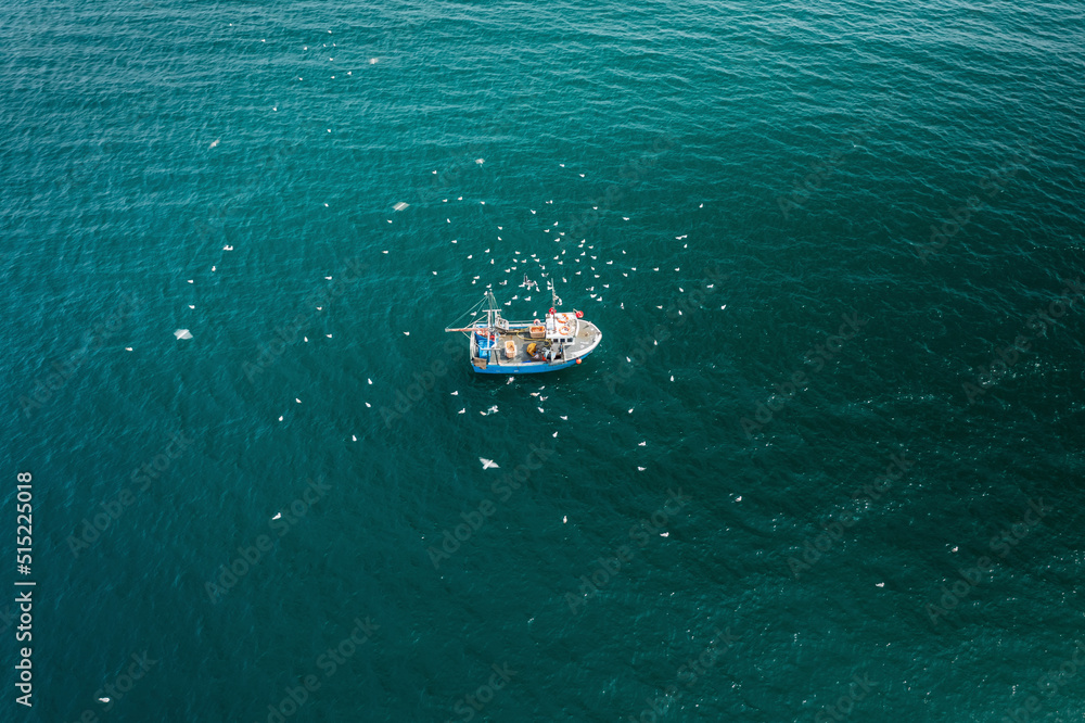 Aerial view of fishing boat in turquoise sea pulling in lobster & crab pots while seagulls fly overhead, Mevagissey, Cornwall, United Kingdom. Aerial view of fishing boat in turquoise sea pulling in lobster & crab pots while seagulls fly overhead, Mevagissey, Cornwall, United Kingdom.