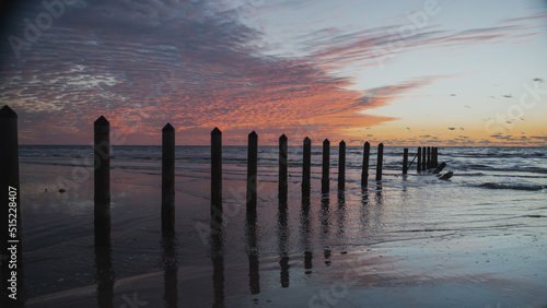 Fototapeta Naklejka Na Ścianę i Meble -  Cloudy early morning at the beach on North Padre Island; Waves rush around pylons
