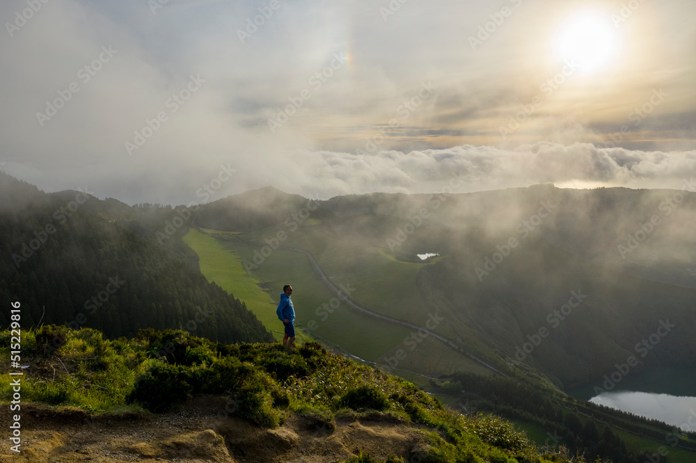 Aerial View of person on the top of the mountain watching Lagoa de Santiago on Miradouro da Boca Aerial View of person on the top of the mountain watching Lagoa de Santiago on Miradouro da Boca