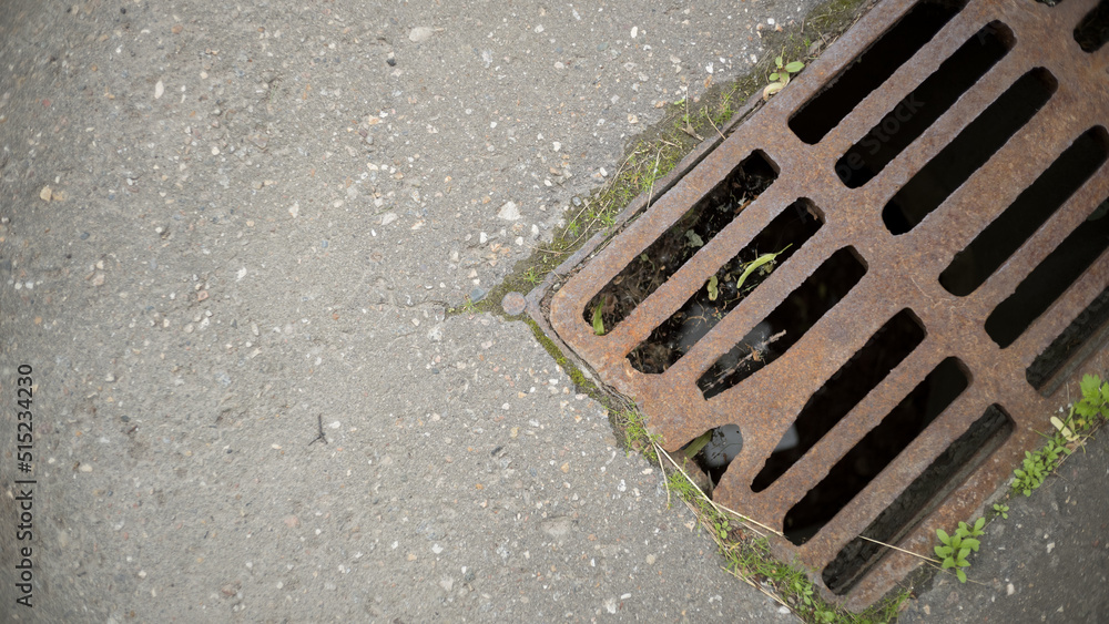Fototapeta premium Old metal sewer grate on an asphalt street, free space