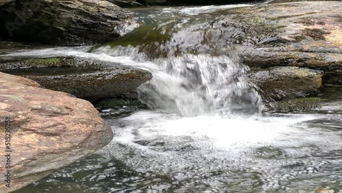 Amazing waterfall in the middle of mountain forest Stones and fresh green leaves.